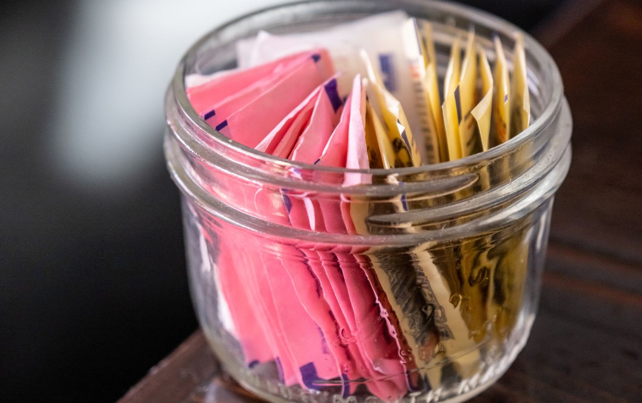 A canister of artificial sweetener packets.