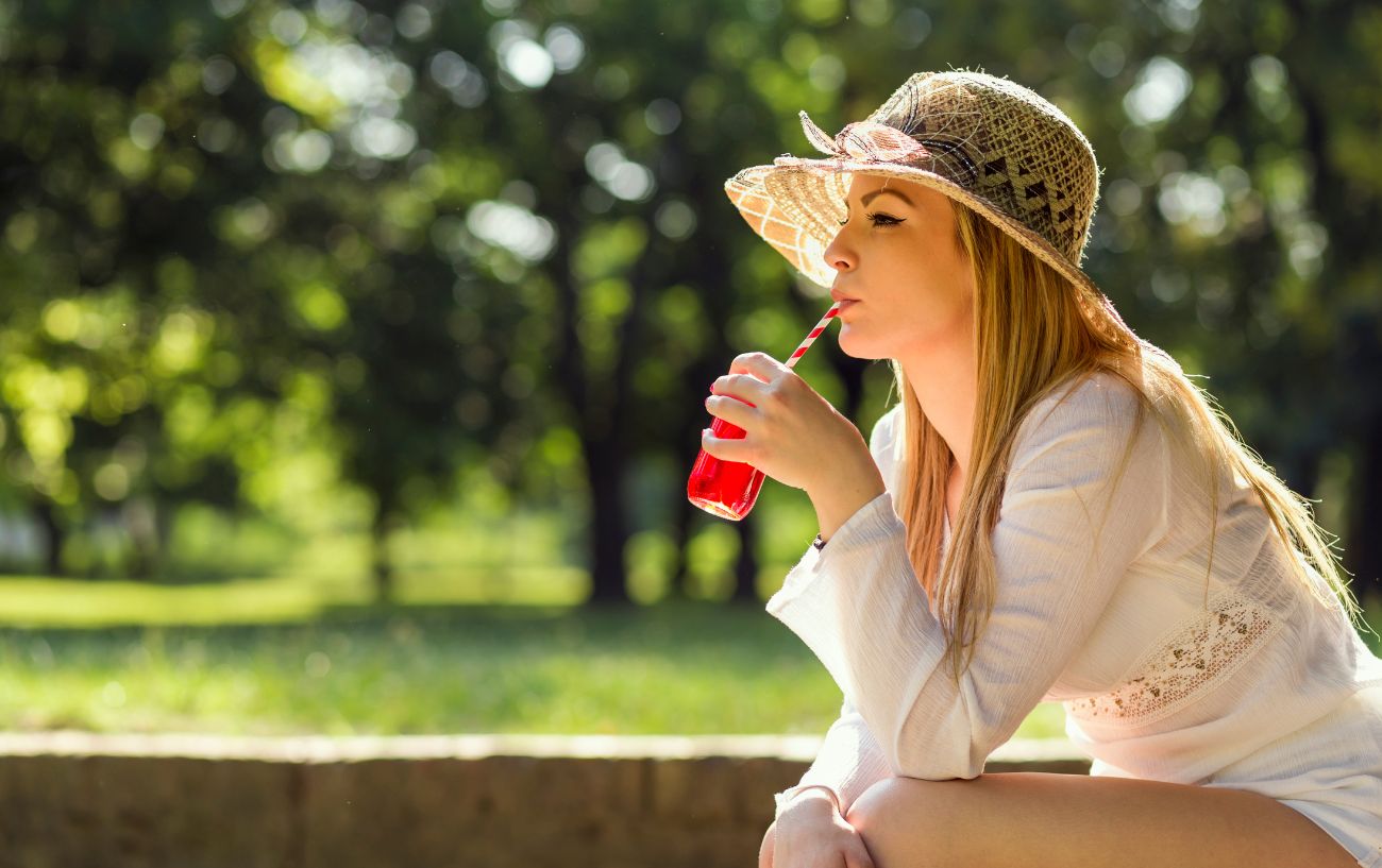 A person drinking beet juice with a straw.