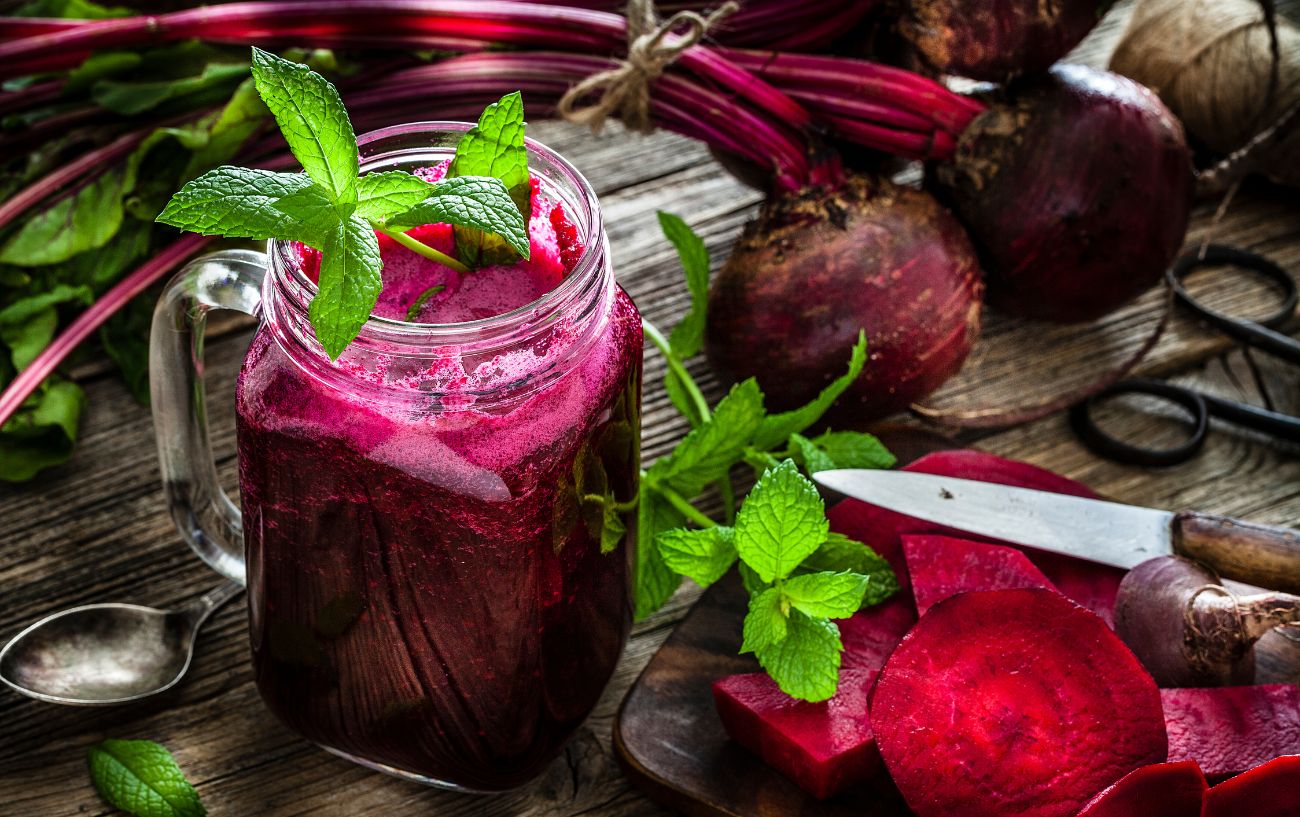 Un vaso de jugo de remolacha y remolachas.