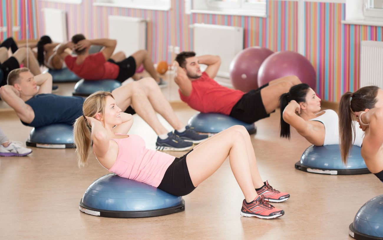 A class of people doing crunches on Bosu balls.