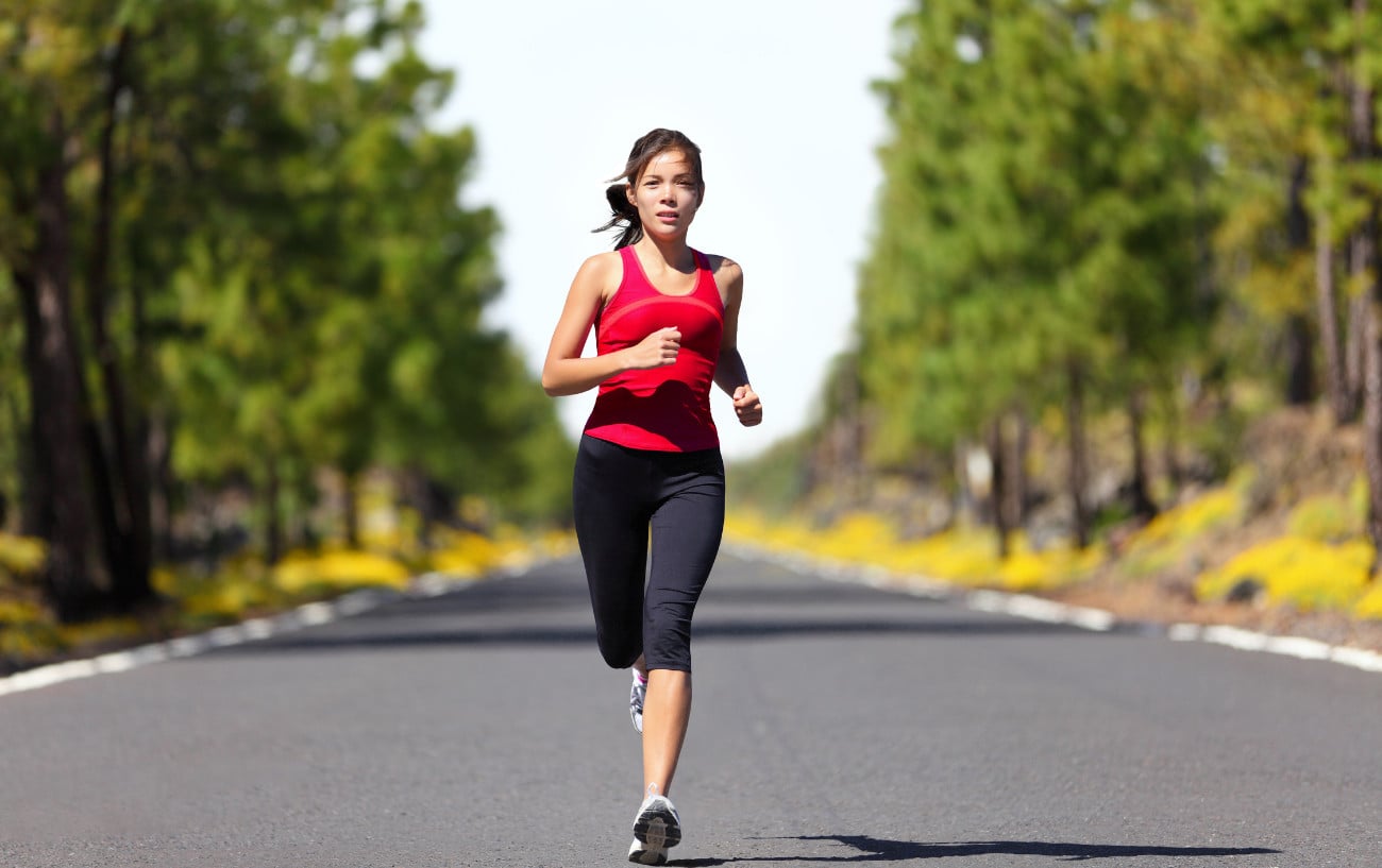 How To Prepare For A Half Marathon: 12 Top Tips From Our Expert Coach 2 A woman running on the road.