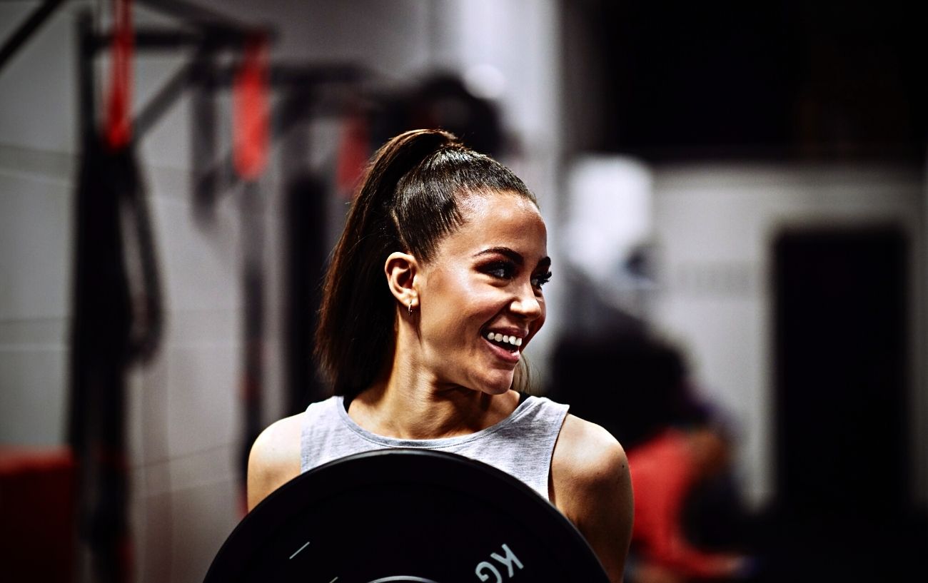 The Ultimate Inner Chest Workout: 6 Inner Chest Exercises To Build Strength 7 A smiling woman doing a plate press.