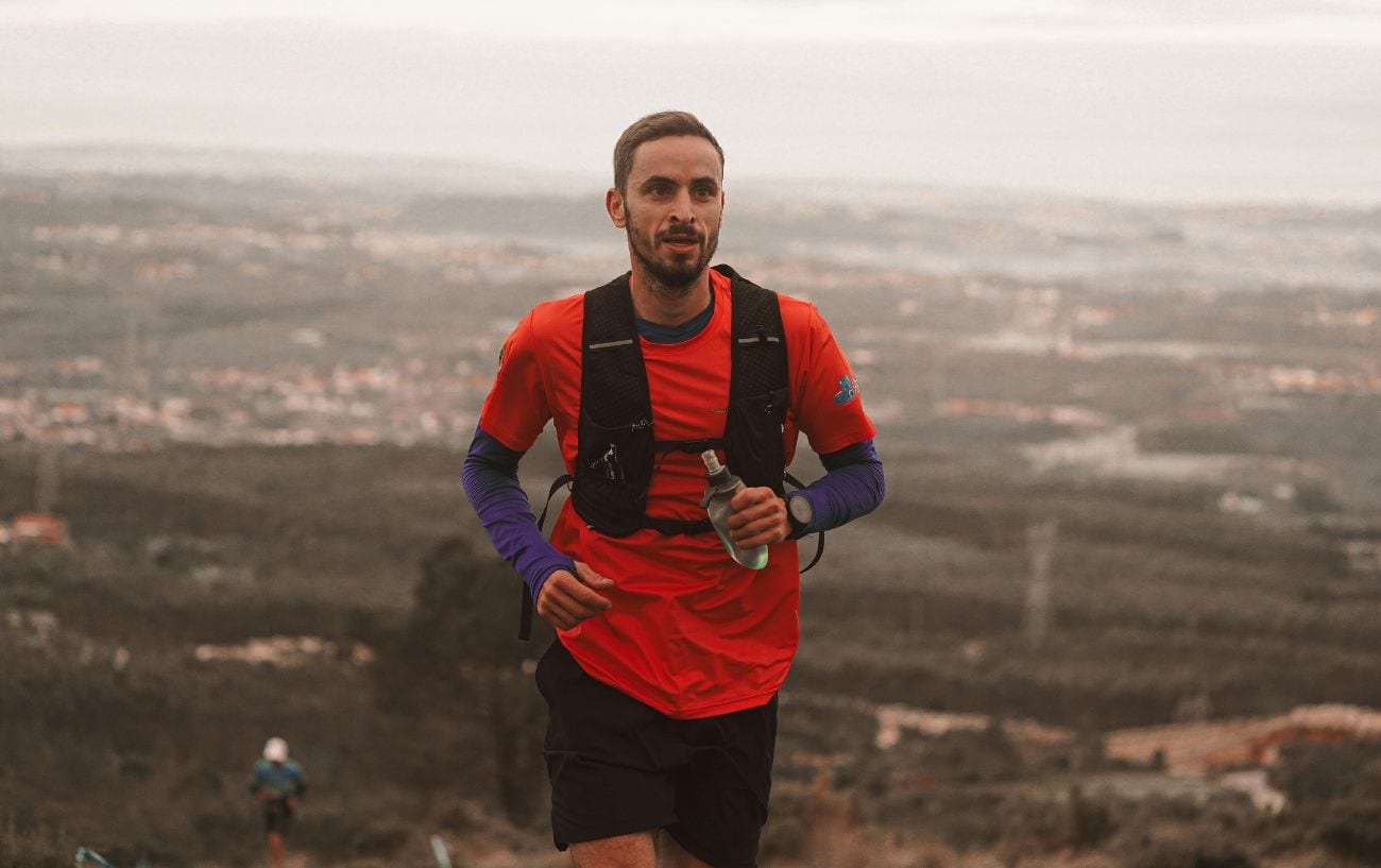 An ultra runner with a pack and carrying a bottle. 