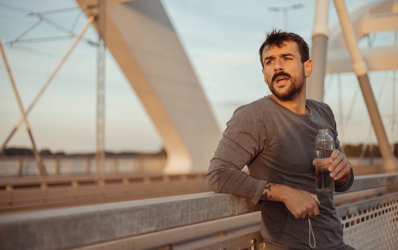 A runner stopped and holding a bottle of water.