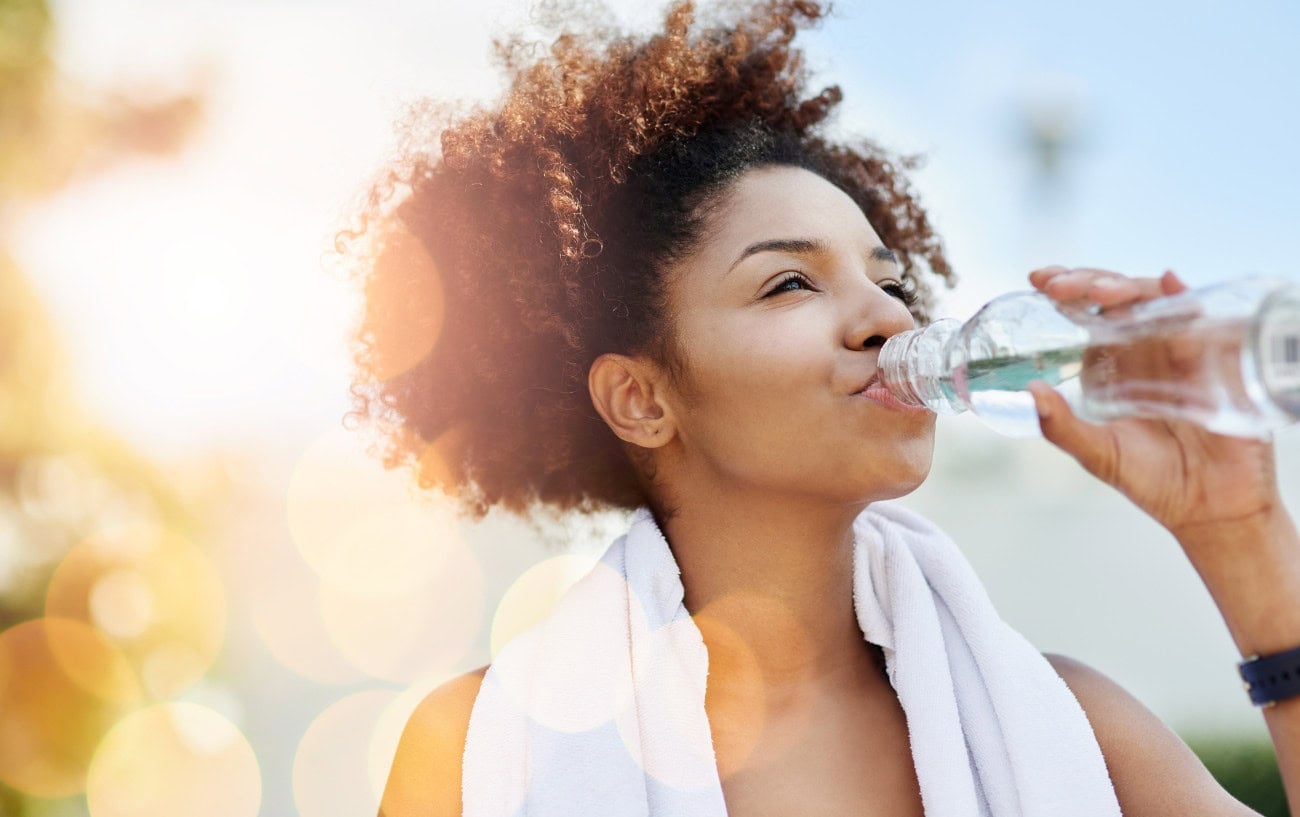 Marathon Training Recovery: How To Recover Quickly After Workouts 5 A woman drinking a bottle of water