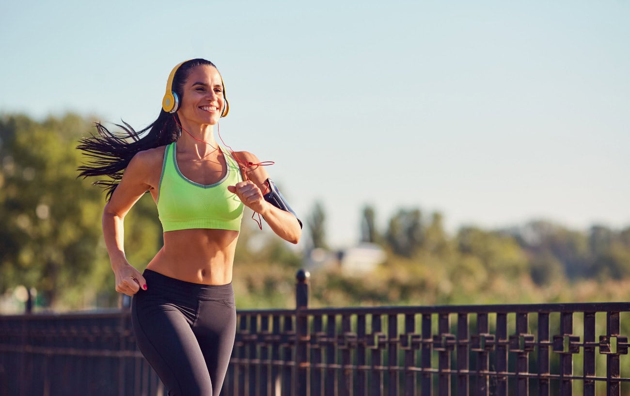 Running Motivation That Works: 11 Tips to Help You Stay on Track 6 Woman jogging in athletic wear outdoors.