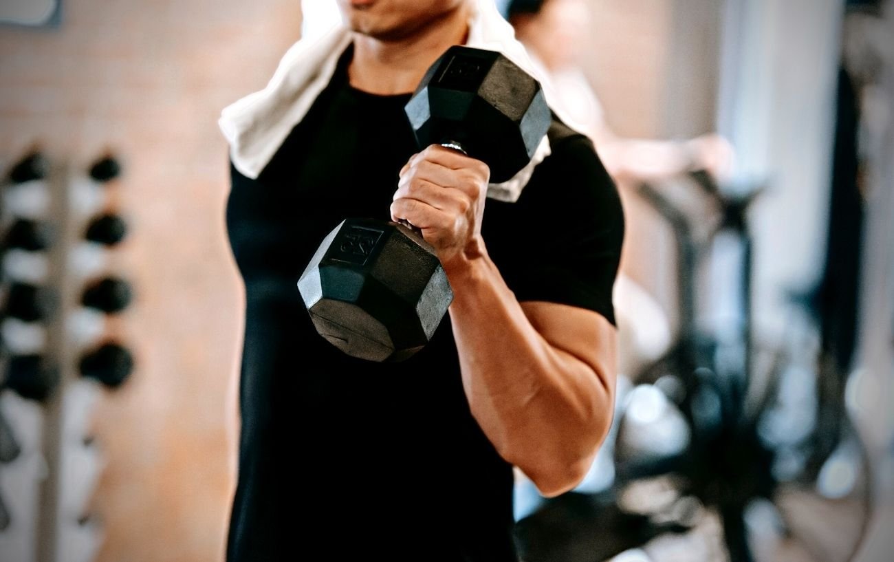 Una persona haciendo un curl de bíceps en el gimnasio.