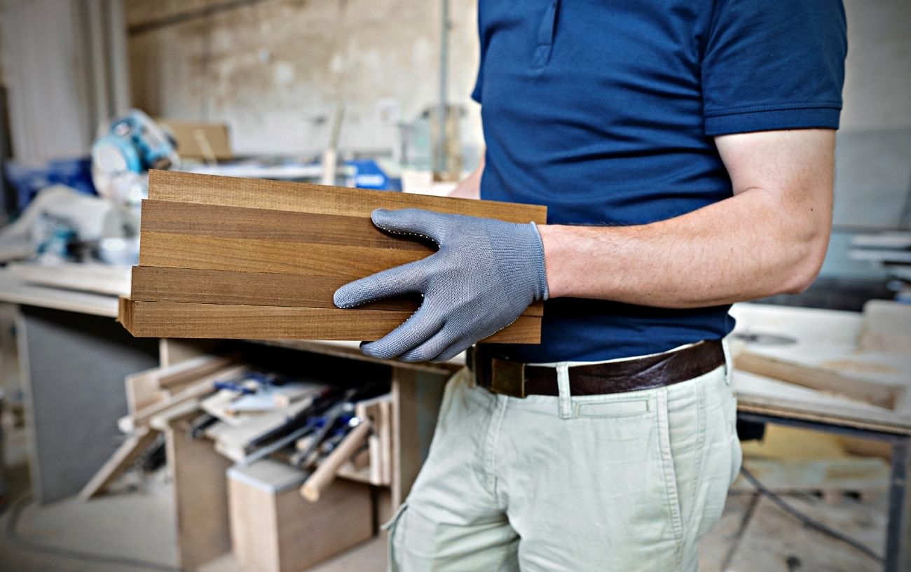 A person carrying wood in a shop.