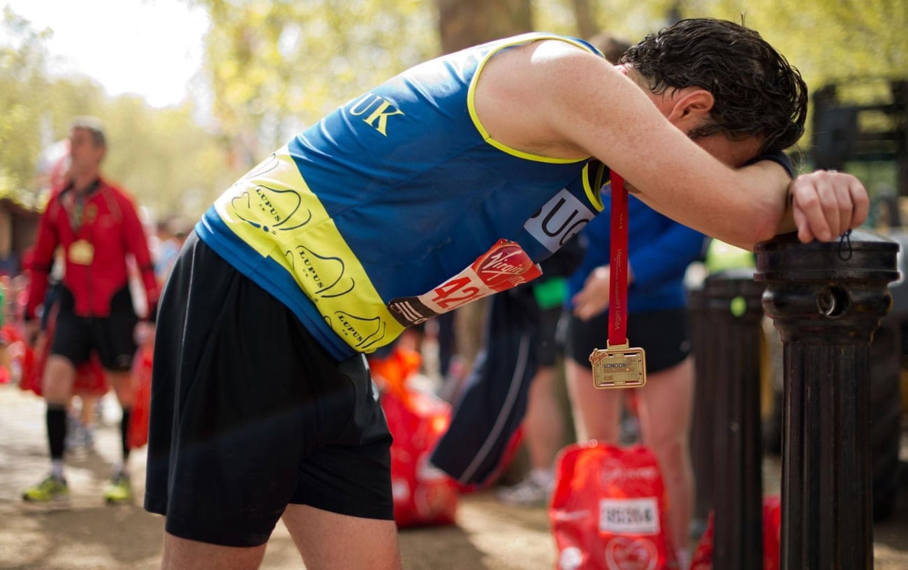 A runner after a race, head in arms bent over.
