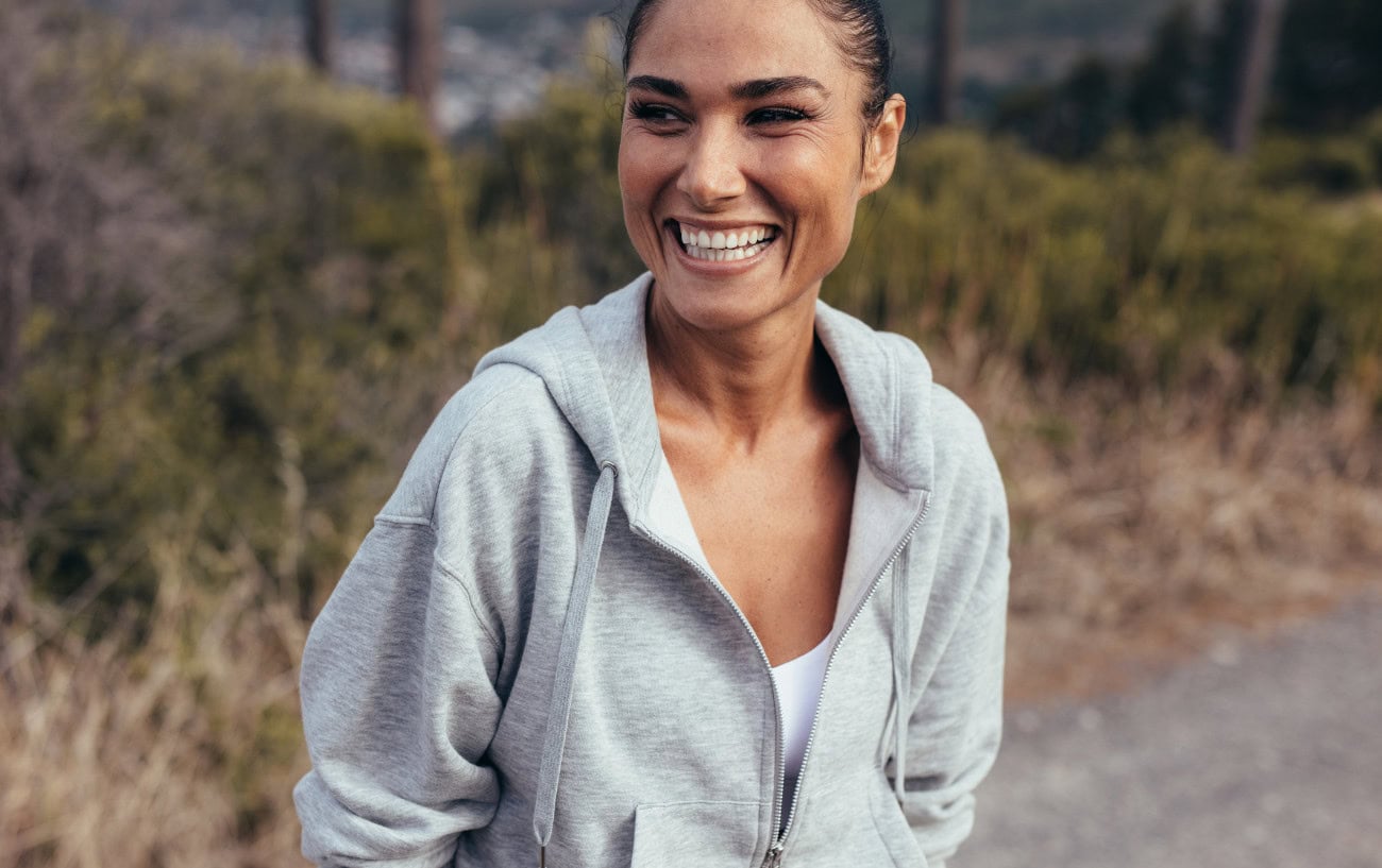 How To Fall Back In Love With Running: Intrinsic Motivation And Smarter Goals 1 A woman smiling.