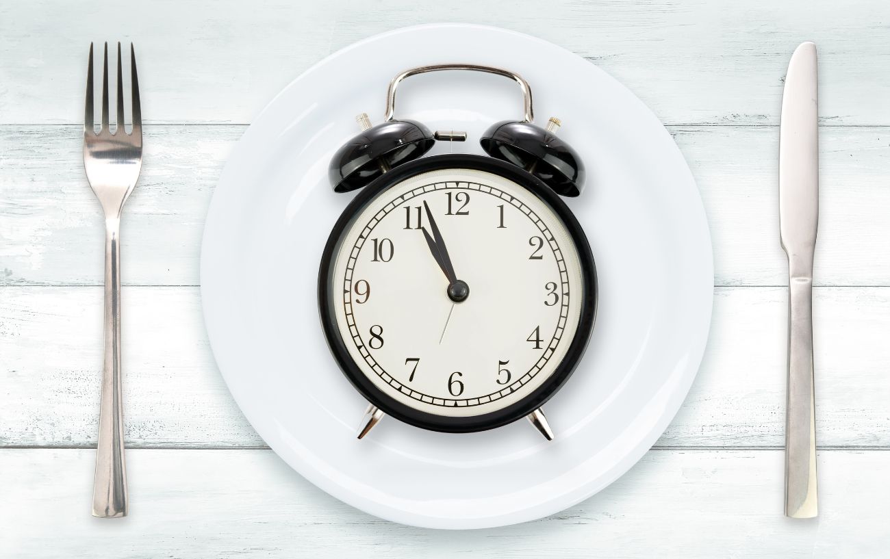 A clock and utensils on an empty plate.