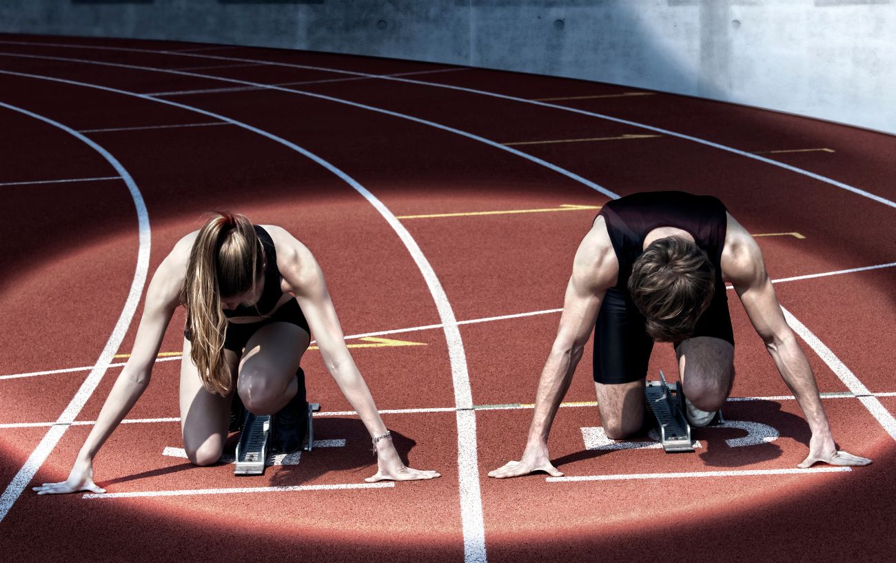 Two people getting ready to sprint on the track.