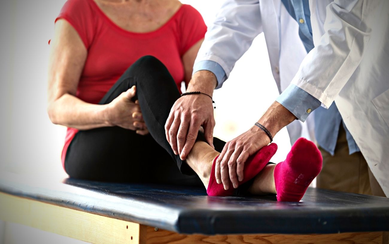 Un médico examinando el tobillo de alguien.