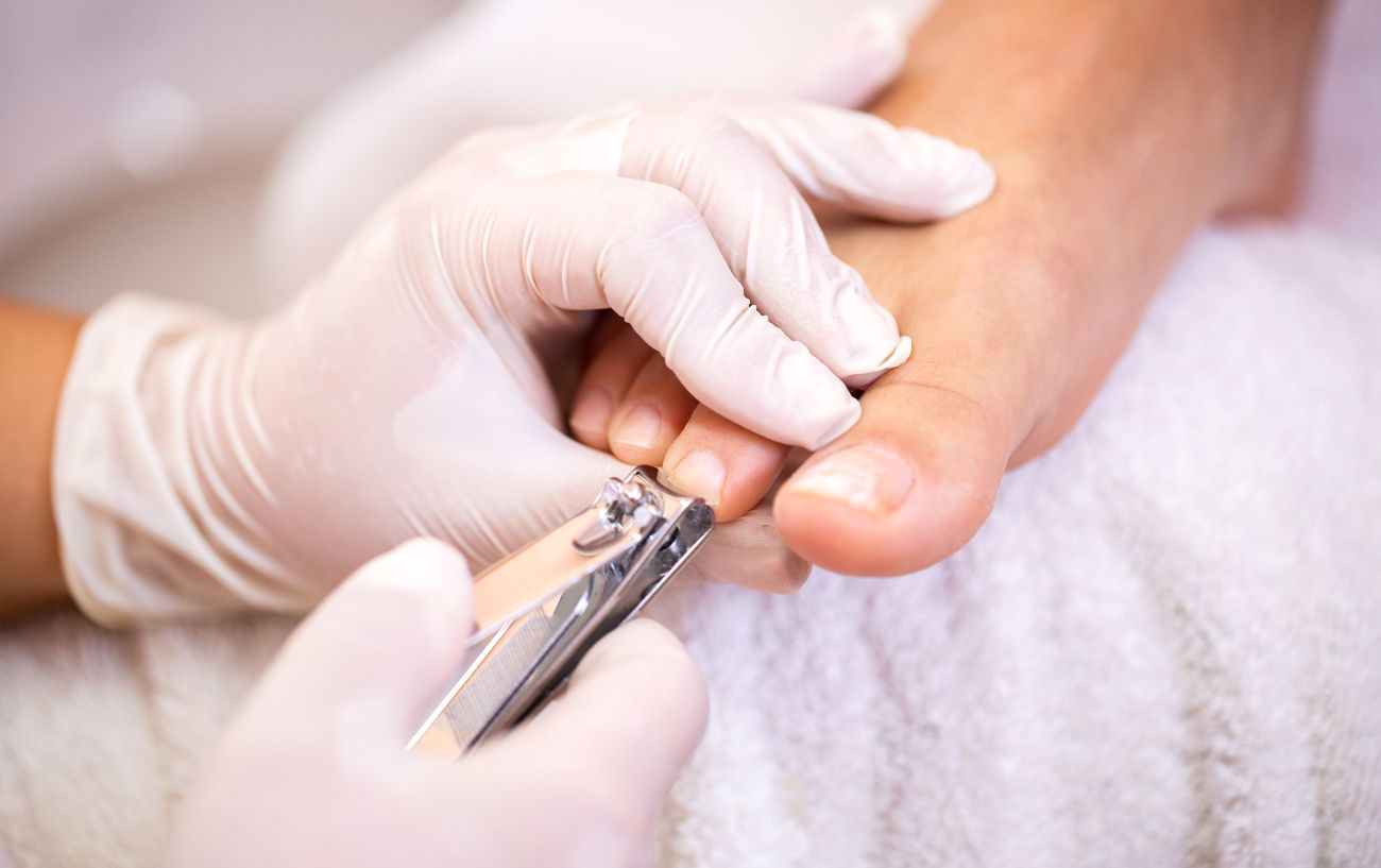 Persona cortándose las uñas de los pies.