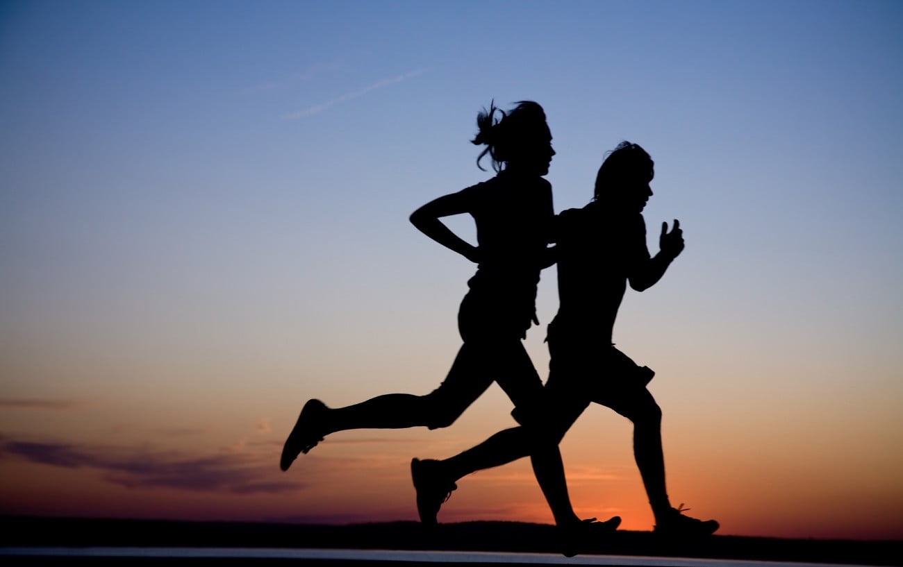 A sillhouette of two people running.