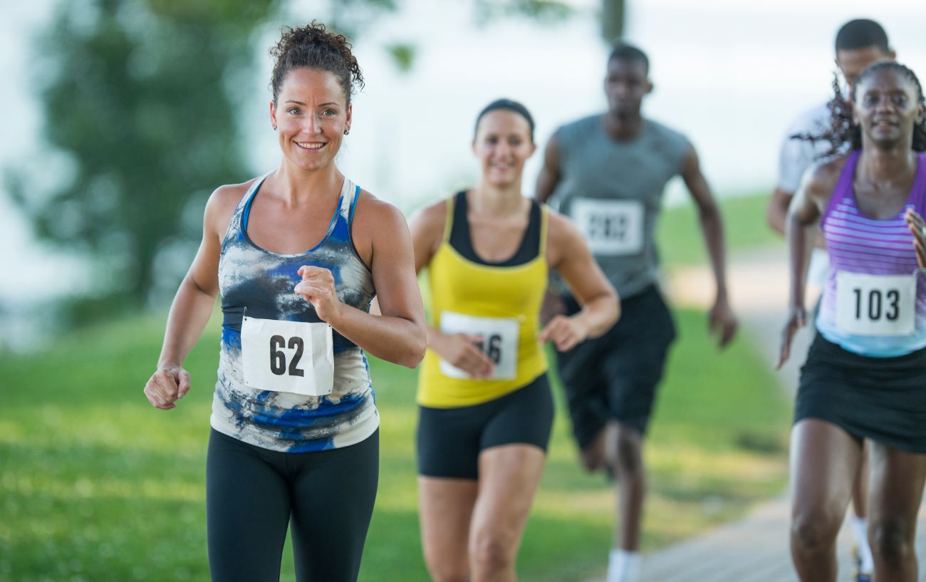 a group of runners smiling as they run through a park