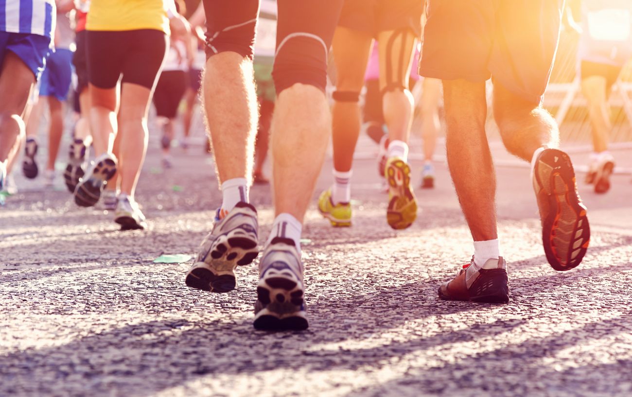 a group of runners' legs on a road