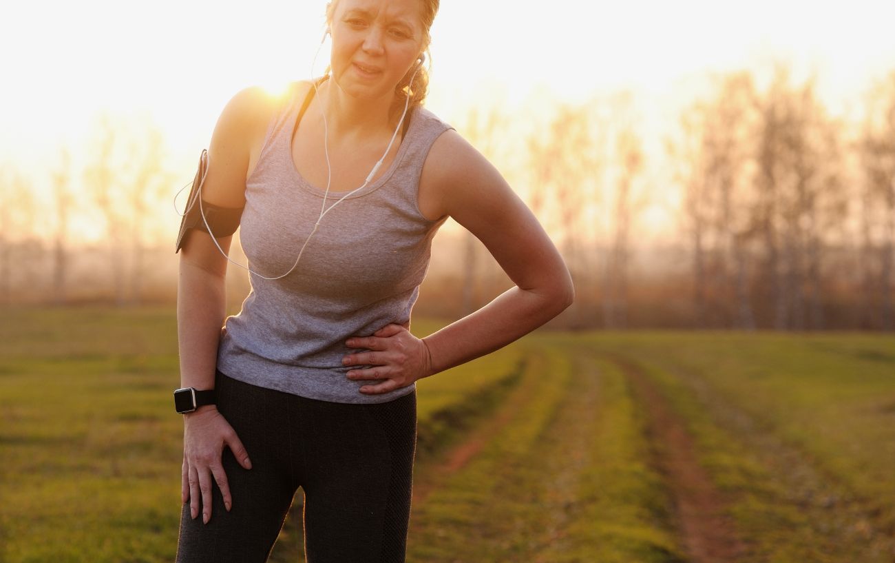 A person holding a side stitch.