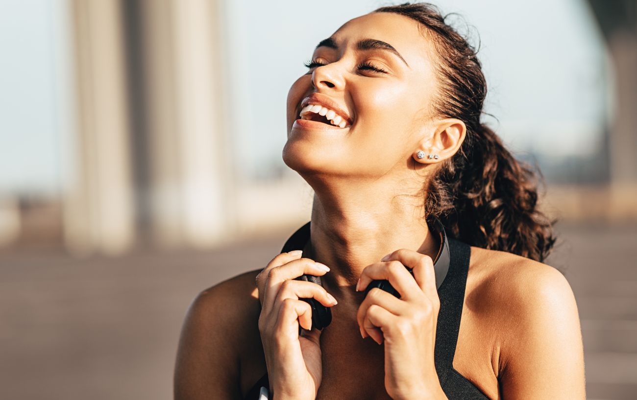 Una corredora sonriendo mientras se quita los auriculares.