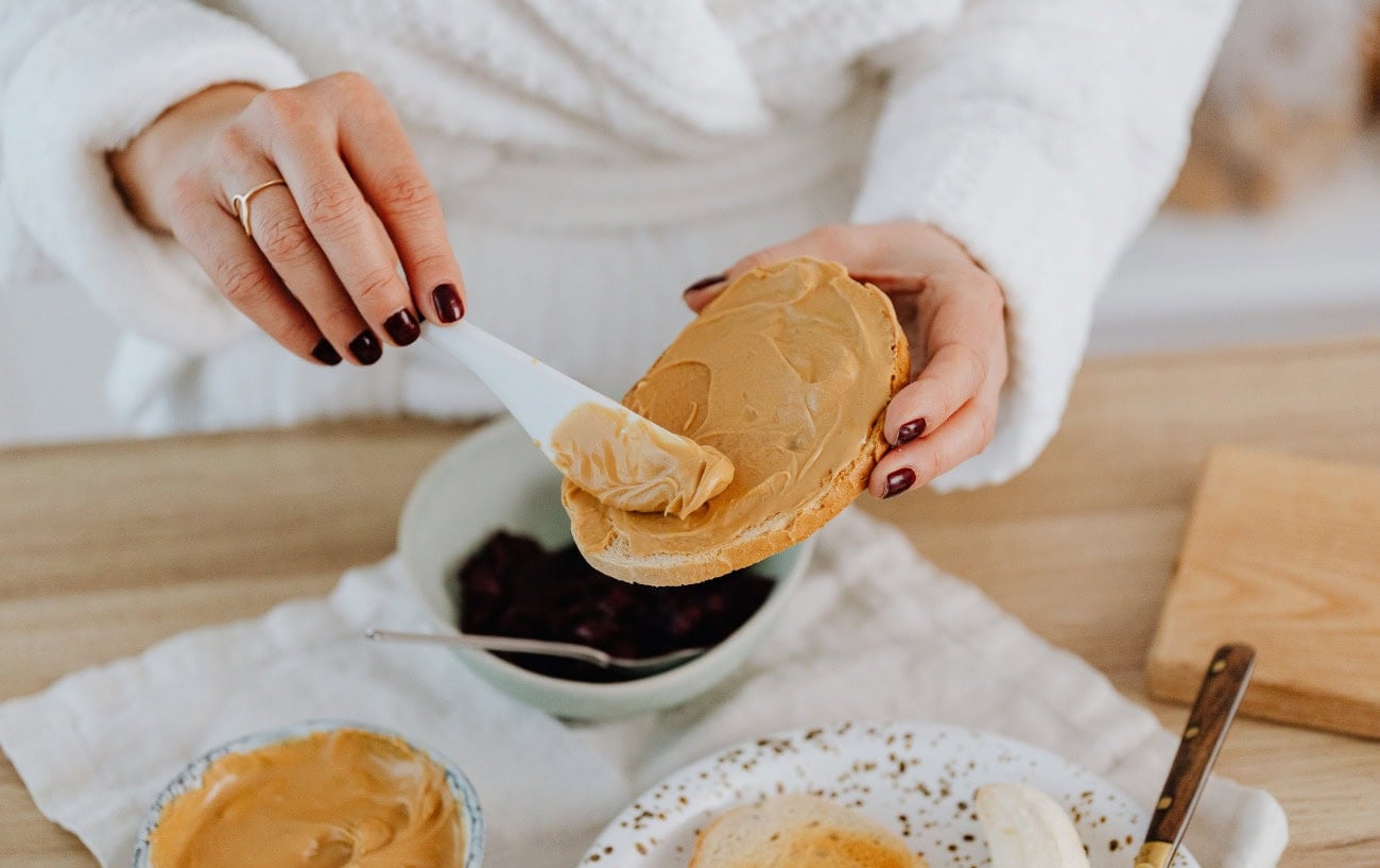 A person spreading peanut butter on toast.
